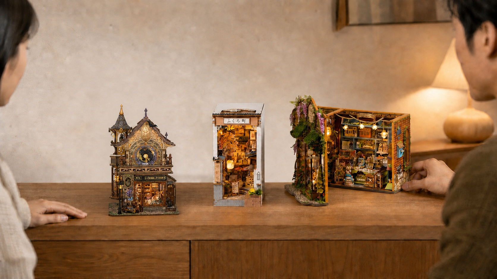 Three similarly sized miniature worlds displayed on one table with friends choosing a favorite