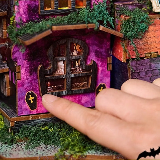 A finger pressing the touch-light control on the side wall of the Halloween Night miniature