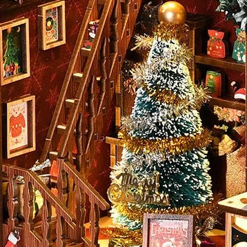 Gold tinsel wraps the tree beside a miniature wooden staircase.