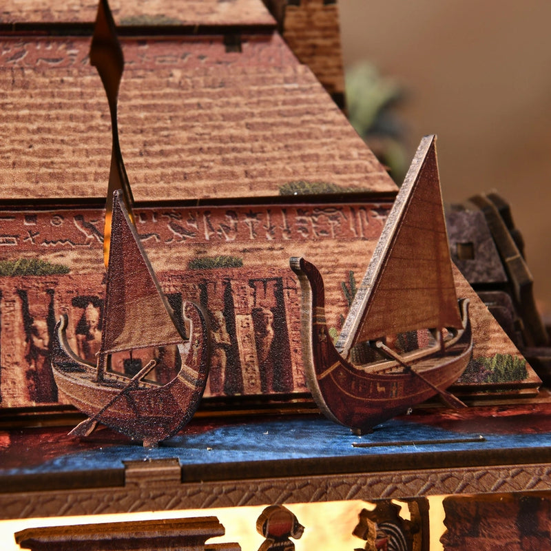 Two tiny sailboats follow the blue river around the pyramid.