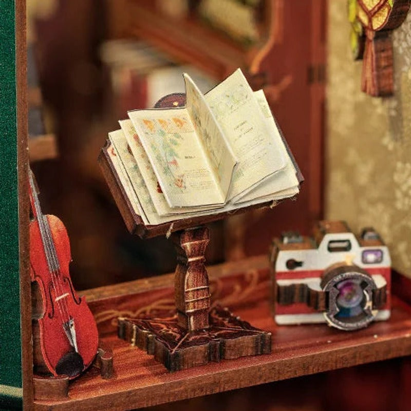 An open book, a tiny violin and a camera by the window.
