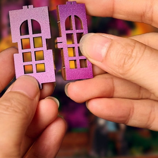 Hands joining two purple tabbed wooden window pieces for the Halloween Night kit