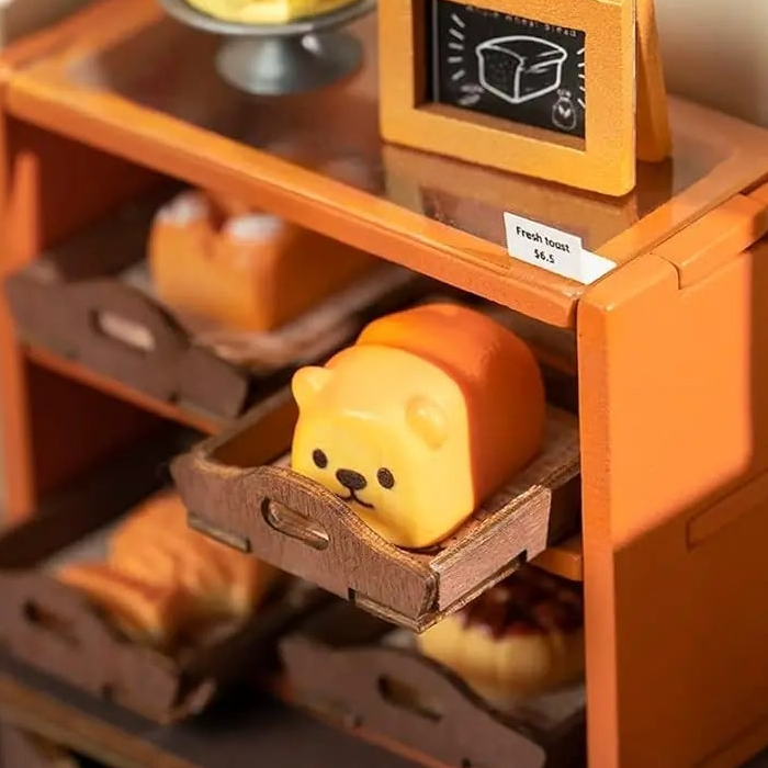 A little bear-faced loaf rests in a tray on the orange shelf.