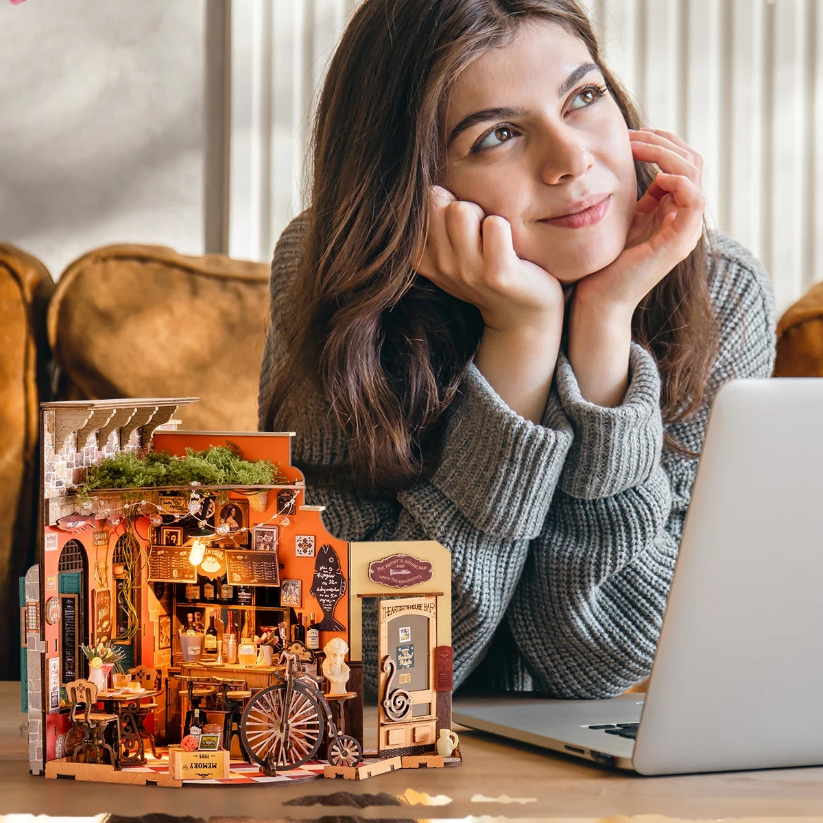 The completed Cheers Bar Dining miniature on a desk beside a woman taking a quiet break