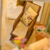A wooden rocking chair with a tiny cushion