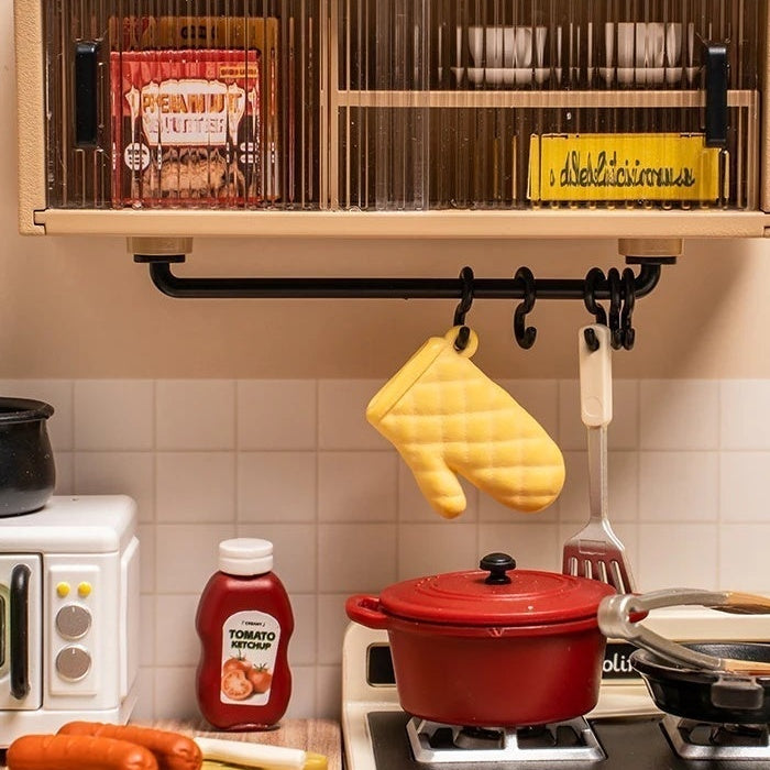 Ribbed clear doors above a yellow mitt and hanging utensils.