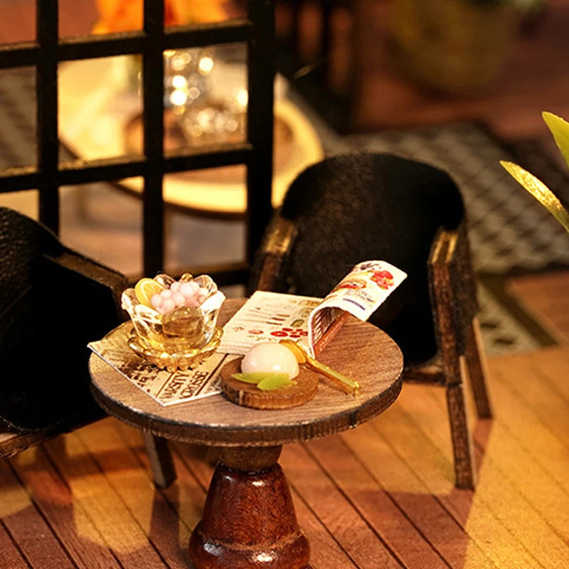 Tiny refreshments and an open magazine between two black chairs.